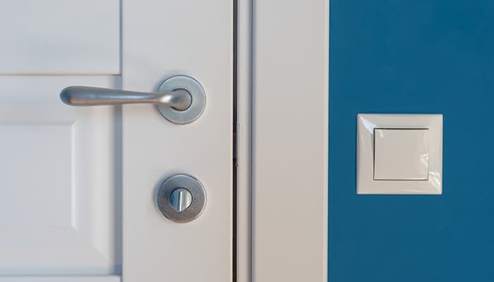 closed door with a silver door handle and a lightswitch