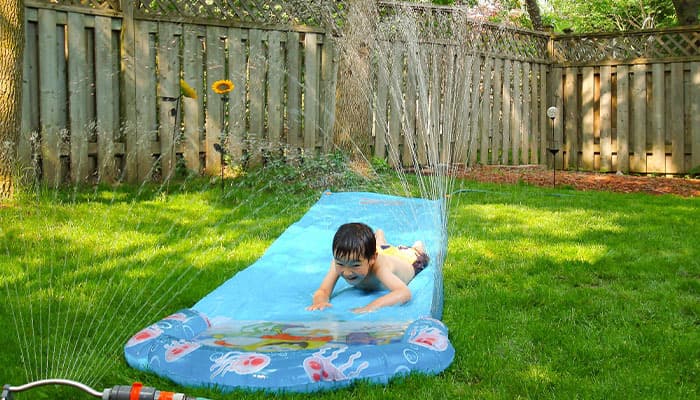 child using a slip and slide in a backgarden