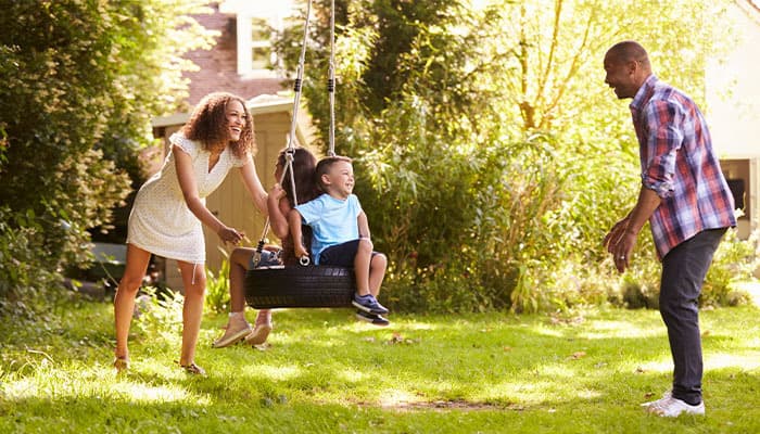 parents pushing children on a swing outdoors